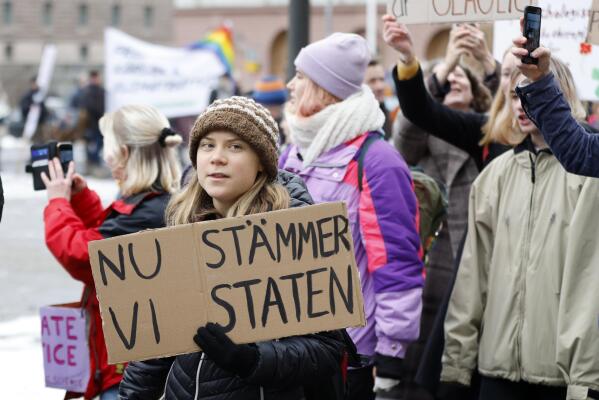 Climate activist Greta Thunberg attends a demonstration by youth-led organization Auroras, in Stockholm, Sweden, Friday, Nov. 25, 2022. Writing on cardboard reads in Swedish "Now we sue the State" (Christine Ohlsson/TT News Agency via AP)