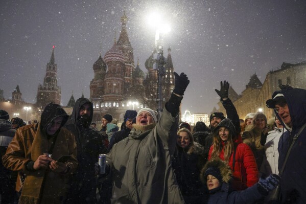 People gather near Red Square with the St. Basil's Cathedral, right, and the Spasskaya Tower, left, in the background, to celebrate the new year after midnight in Moscow, Russia, Monday, Jan. 1, 2024. (AP Photo/Marina Lystseva)