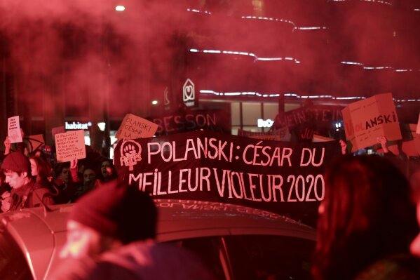 Women protest with abanner reading "Polanski: Cesar for the Best Raper 2020" near the venue of the Cesar awards ceremony, the French equivalent of the Oscar, Friday, Feb. 28, 2020 in Paris. Women's rights activists protested outside the Paris concert hall where France's film academy is presenting its version of the Oscars and director Roman Polanski's latest film is up for the most awards. (AP Photo/Rafael Yaghobzadeh)