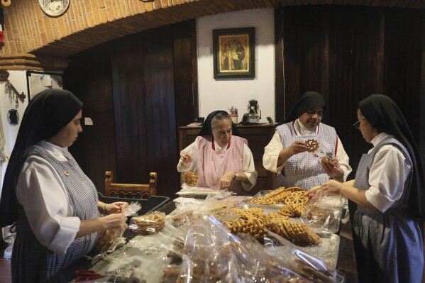 From left, nuns Alejandra Jaime, 39, Maria Ines Maldonado, 76, Maria Auxiliadora Estrada, 59, and Patricia Marin, 28, store fritters with Christmas figures in clear plastic bags for sale at the Convent of the Mothers Perpetual Adorers of the Blessed Sacrament in Mexico City, Thursday, Dec. 7, 2023. (AP Photo/Ginnette Riquelme)