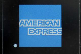 An American Express logo is attached to a door in Boston's Seaport District, Wednesday, July 21, 2021. Credit card company American Express said Tuesday, Jan. 25, 2022, that its fourth quarter profits rose 20% from a year earlier, as eager consumers spent record levels of money during the holiday season on the company’s namesake cards. (AP Photo/Steven Senne)