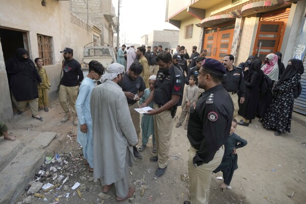 A Police officer checks documents of a resident during a search operation against illegal immigrants, at a neighborhood of Karachi, Pakistan, Thursday, Nov. 2, 2023. Pakistani security forces have rounded up, detained and deported dozens of Afghans who were living in the country illegally, after a government-set deadline for them to leave expired, authorities said. (AP Photo/Fareed Khan)