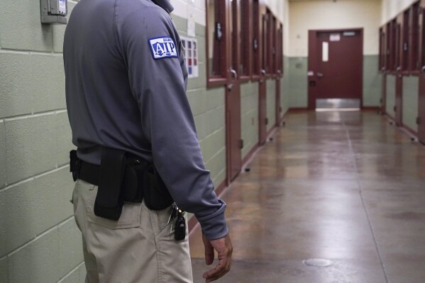A security guard poses for a photo next to the group holding cells during a media tour of the Port Isabel Detention Center (PIDC), hosted by U.S. Immigration and Customs Enforcement (ICE) and Harlingen Enforcement and Removal Operations (ERO) in Los Fresnos, Texas, June 10, 2024. (Veronica Gabriela Cardenas/Pool Photo via AP, File)