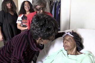 FILE - In this Sept. 22, 2018 file photo, Lessie Brown, right, is visited by her daughters, Verline Wilson, foreground, and Vivian Hatcher, third from left, and other family and friends at her home in Cleveland Heights, Ohio. A grandson said Brown, the 114-year-old Ohio woman who was believed to be the oldest person in the United States, died Tuesday. Jan. 8, 2019. (David Petkiewicz/The Plain Dealer via AP)