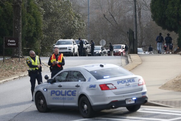 Athens-Clarke County police block traffic and investigate at the UGA intramural Fields after the body of a women was found with found with visible injuries was found in the woods around Lake Herrick in Athens, Ga., on Thursday, Feb. 22, 2024. (Joshua L. Jones/Athens Banner-Herald via AP)