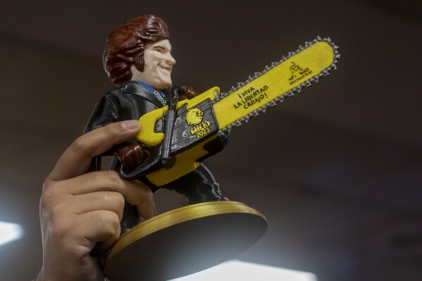 A supporter of presidential hopeful with the Liberty Advances coalition, Javier Milei, holds a statue of the candidate holding a chainsaw that reads in Spanish "Long live freedom!" while waiting for him at the airport in Salta, Argentina, Thursday, Oct. 12, 2023. Elections are set for Oct. 22. (AP Photo/Javier Corbalan)