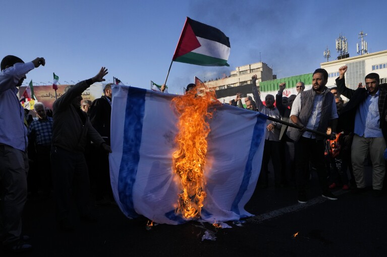 FILE - Iranian demonstrators burn a representation of the Israeli flag as one of them waves a Palestinian flag in a pro-Palestinian rally at Enqelab-e-Eslami (Islamic Revolution) Sq. in Tehran, Iran, Saturday, Nov. 18, 2023. (AP Photo/Vahid Salemi, File)