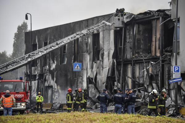 Firefighters work on the site of a plane crash, in San Donato Milanese suburb of Milan, Italy, Sunday, Oct. 3, 2021. According to media reports, a small plane carrying five passengers and the pilot crashed into an apparently vacant office building in a Milan suburb. Their fates were not immediately known. (Claudio Furlan/LaPresse via AP)