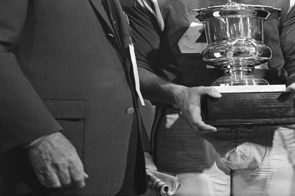 FILE - Van C. Kussrow, left, from the Orange Bowl Committee, presents Baltimore Colts quarterback Tom Matte with the Most Valuable Player trophy after the Colts defeated the Dallas Cowboys 53-3 on Jan. 9, 1966, in Miami.  Matte, who spent his entire 12-year NFL career as a gritty running back for the Baltimore Colts _ except for a star turn for three games in 1965 as their quarterback _ has died. He was 82. The Baltimore Ravens confirmed Matte's death during coach John Harbaugh's news conference Wednesday, Nov. 3, 2021. No details were provided.(AP Photo/File)