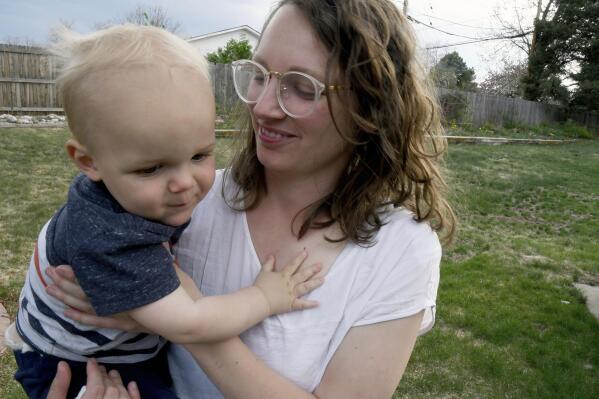 Sarah Perkins holds her 1-year-old son, Cal Sabey, at a relative's home in Centennial, Colo., Wednesday, May 3, 2023. Perkins and her husband are suing police and social workers in Massachusetts after their two young children were taken by the state's Department of Children and Families in July 2022. Hospital staff discovered that Cal had suffered a broken rib and flagged the couple for possible child abuse. The couple's lawsuit alleges constitutional violations including the unreasonable search of their house, the unreasonable seizure of their children and the deprivation of parental rights without due process. (AP Photo/Thomas Peipert)