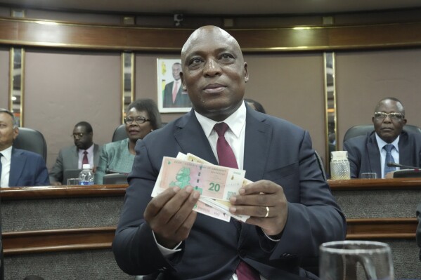 Reserve Bank of Zimbabwe Governor, John Mushayavanhu holds a sample of the country's new currency at a press briefing in Harare, Friday, April 5, 2024. Zimbabwe on Friday launched a new currency to replace a local unit that in recent months has been battered by depreciation, and in some instances rejected by the population, and authorities hope the new measure will arrest the currency crisis underlining the country's years long economic troubles. (AP Photo/Tsvangirayi Mukwazhi)