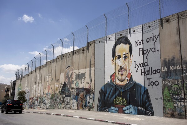 FILE - A mural depicting Eyad Hallaq, an autistic Palestinian man who was killed by Israeli police in Jerusalem's Old City last year, is seen on Israel's controversial separation barrier, in the West Bank town of Bethlehem, Friday, April 9, 2021. A growing number of Black Americans see the struggle of Palestinians reflected in their own fights for freedom and civil rights. In recent years, the rise of protest movements in the U.S. against police brutality in the U.S., where structural racism plagues nearly every facet of life, has connected Black and Palestinian activists under a common cause. But that kinship sometimes strains the alliance between Black and Jewish activists, which extends back several decades. (AP Photo/Maya Alleruzzo, File)