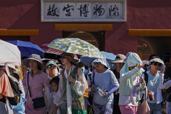 Visitors wear sun hats and carry umbrellas as they leave the Forbidden City on a hot day in Beijing, Thursday, June 29, 2023. (AP Photo/Andy Wong)