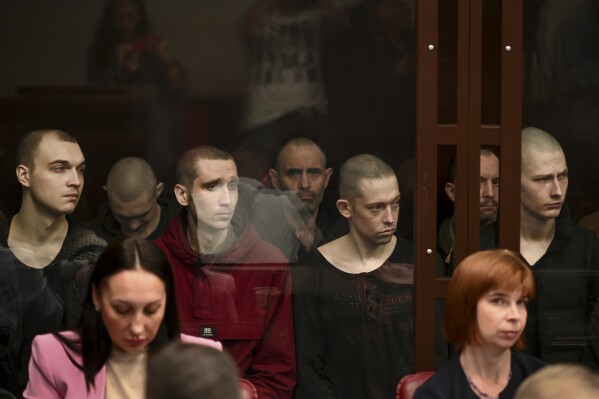 Ukrainian soldiers who were taken prisoner during fighting sit inside a defendant's glass cage during a hearing at the Southern District Military Court in Rostov-on-Don, Russia, Wednesday, June 14, 2023. More than 20 Ukrainian soldiers who were taken prisoner during fighting in Ukraine are facing trial in southern Russia. The captured soldiers were members of the Azov battalion that fought Russian troops in the Sea of Azov port of Mariupol last year. (AP Photo)