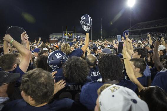 Georgia Southern fans and players celebrate at midfield after defeating James Madison during an NCAA football game, Saturday, Oct. 15, 2022, in Statesboro, Ga.. (AP Photo/Stephen B. Morton)