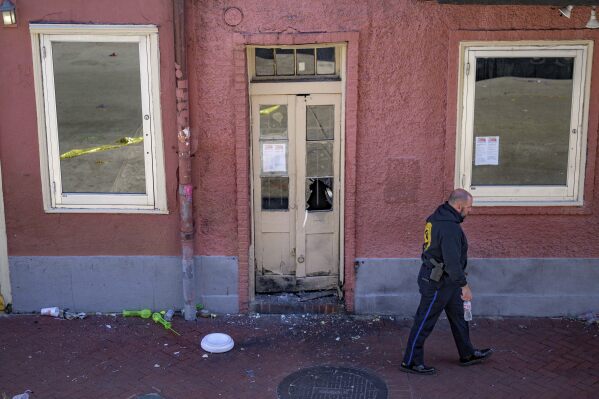 An New Orleans Police officer walks past a damaged doorway after members of the FBI and bomb squad detonated a suspicious package damaging the doorway according to an eyewitness on Bourbon Street during the investigation of truck crashing into pedestrians on Bourbon Street in the French Quarter in New Orleans, Wednesday, Jan. 1, 2025. The white lid of a blue cooler that the surveillance footage showed the suspect placing on Bourbon before the attack by Club 544 is below the doorway at Bourbon Street near Toulouse Street. (AP Photo/Matthew Hinton)
