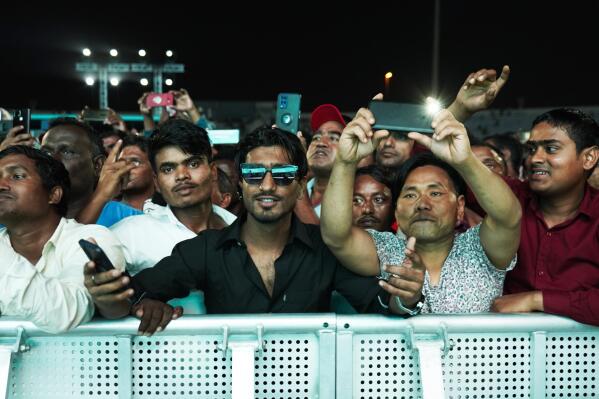 Laborers cheer at a fan festival at the Asian Town cricket stadium in Doha, Qatar, Friday, Nov. 25, 2022. Far from the luxury hotels and sprawling new stadiums emblematic of Doha during the World Cup, scores of soccer-mad South Asian workers poured into a converted cricket stadium in the city's desert outskirts to enjoy the tournament they helped create. (AP Photo/Jon Gambrell)