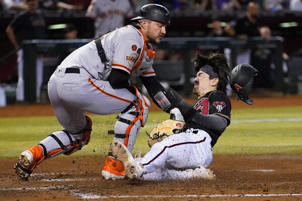 Arizona Diamondbacks' Corbin Carroll, right, scores on a throwing error after stealing third during the second inning of a baseball game as San Francisco Giants catcher Patrick Bailey tries to make the tag, Tuesday, Sept. 19, 2023, in Phoenix. (AP Photo/Matt York)