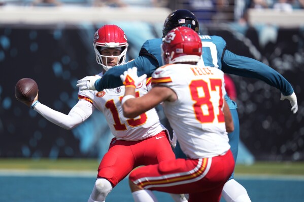 Kansas City Chiefs quarterback Patrick Mahomes (15) tries to throw to tight end Travis Kelce (87) as he is pressured by Jacksonville Jaguars defensive end Angelo Blackson, center, during the second half of an NFL football game, Sunday, Sept. 17, 2023, in Jacksonville, Fla. (AP Photo/John Raoux)