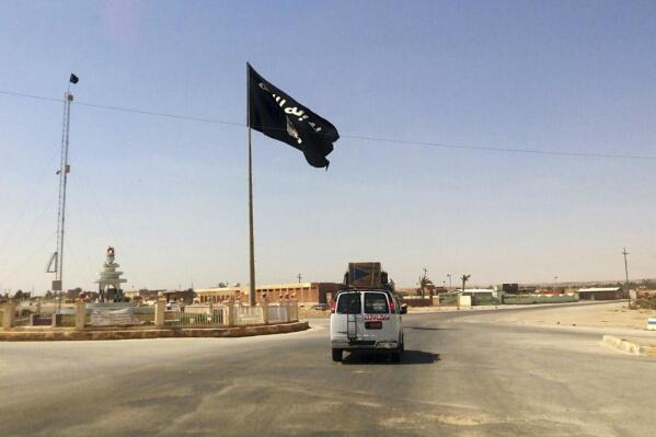 FILE - A vehicle passes by a flag of the Islamic State group in central Rawah, 175 miles (281 kilometers) northwest of Baghdad, Iraq. U.N. investigators are compiling evidence on the development and use of chemical weapons by Islamic State extremists in Iraq after they seized about a third of the country in 2014, and are advancing work on the militant group’s gender-based violence and crimes against children, Sunni and Shiite Muslims, Christians and Yazidis, the head of the investigative team said Wednesday, June 7, 2023. (AP Photo/File)