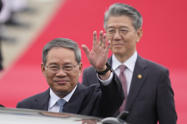 Chinese Premier Li Qiang, left, waves to media members before getting into a car as Kim Hong-kyun, right, South Korean 1st vice foreign minister, follows behind at the Seoul airport in Seongnam, South Korea, Sunday, May 26, 2024, as the premier arrives for a trilateral meeting. Leaders of South Korea, China and Japan will meet next week in Seoul for their first trilateral talks since 2019. (AP Photo/Lee Jin-man)