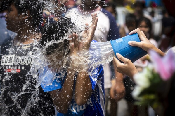 A man reacts as a bucket of water is splashed on him during the Songkran water festival to celebrate the Thai New Year in Prachinburi Province, Thailand, Saturday April 13, 2024. It's the time of year when many Southeast Asian countries hold nationwide water festivals to beat the seasonal heat, as celebrants splash friends, family and strangers alike in often raucous celebration to mark the traditional Theravada Buddhist New Year. (AP Photo/Wason Wanichakorn)