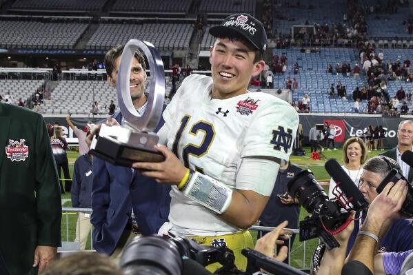 Notre Dame quarterback Tyler Buchner (12) holds with the MVP trophy after the team's Gator Bowl NCAA college football game against South Carolina on Friday, Dec. 30, 2022, in Jacksonville, Fla. Notre Dame won 45-38. (AP Photo/Gary McCullough)