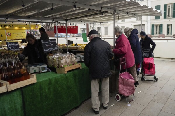 People shop at an open air market in Fontainebleau, south of Paris, France, Friday, Feb 2, 2024. European farmers and households are both hurting these days because of multiple factors, including persistent inflation, high interest rates and volatile energy prices. (AP Photo/Thibault Camus)