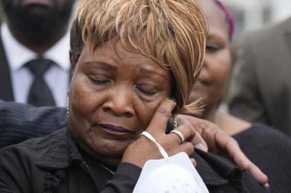 Bettersten Wade, mother of Dexter Wade, a 37-year-old man who died after being hit by a Jackson, Miss., police SUV driven by an off-duty officer, wipes away tears as she watches her son's body transferred to a mortuary transport, after being exhumed from a pauper's cemetery near the Hinds County Penal Farm in Raymond, Monday, Nov. 13, 2023. Civil rights attorney Ben Crump said Monday he is asking the U.S. Justice Department to investigate why authorities waited several months to notify the family of his death. (AP Photo/Rogelio V. Solis)