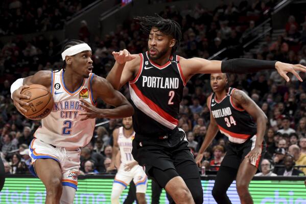 Oklahoma City Thunder guard Shai Gilgeous-Alexander, left, drives to the basket on Portland Trail Blazers forward Trendon Watford (2) during the first half of an NBA basketball game in Portland, Ore., Friday, Feb. 10, 2023. (AP Photo/Steve Dykes)