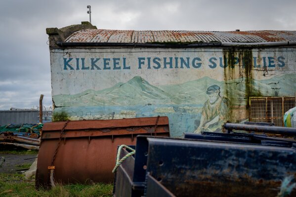 FILE - In this Tuesday, Jan. 28, 2020 file photo, old fishing equipment rusts away in front of old hand painted advertisement for fishing supplies at Kilkeel harbour in Northern Ireland. Fishing stands in the way of a massive trade deal between the European Union and recently departed Britain, putting at risk hundreds of thousands of jobs and tens of billions of euros in annual production losses. (AP Photo/David Keyton, File)