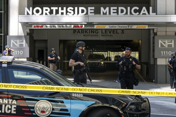 FILE - Law enforcement officers stand Northside Hospital Midtown medical office building, where a man opened fire in the medical center waiting room, killing one woman and wounding four, on May 3, 2023, in Atlanta. Data shows American health care workers now suffer more nonfatal injuries from workplace violence than workers in any other profession, including law enforcement. (Arvin Temkar/Atlanta Journal-Constitution via AP)