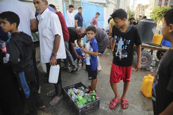 FILE - Palestinians fetch water in the Nuseirat camp in the central Gaza Strip during ongoing Israeli bombardments, Tuesday, October 17, 2023. As the war between Israel and Hamas comes to an end, its second month and more than 10,000 people are killed in Gaza, trapped civilians struggle to survive without electricity or running water.  Every day became a mind-numbing cycle of searching for bread and water and waiting in line.  A sense of hopelessness is straining Gaza's close-knit society.  (AP Photo/Ali Mohmoud, file)