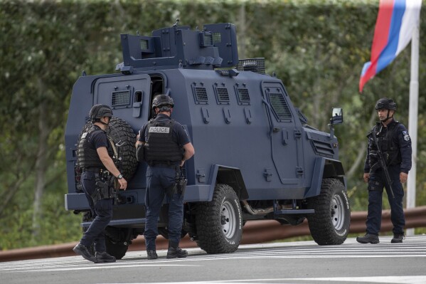 Kosovo police officers seen near an armored vehicle secure a cross road leading to the Banjska Monastery in the village of Banjska on Sunday, Sept.24, 2023. Kosovo's prime minister on Sunday said one police officer was killed and another wounded in an attack he blamed on support from neighboring Serbia, increasing tensions between the two former war foes at a delicate moment in their European Union-facilitated dialogue to normalize ties. (AP Photo/Visar Kryeziu)