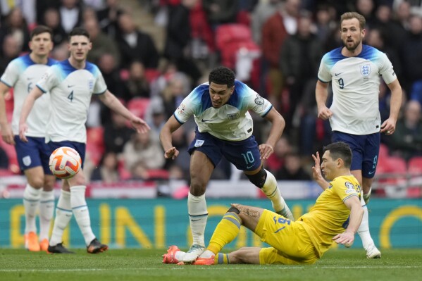 FILE -Ukraine's Taras Stepanenko, bottom, challenges for the ball with Englands' Jude Bellingham, centre, during the Euro 2024 group C qualifying soccer match between England and Ukraine in London, Sunday, March 26, 2023. With four of the hottest forwards in European soccer, England has no shortage of firepower as it looks to end a near-60-year wait for silverware. (AP Photo/Alastair Grant, File)