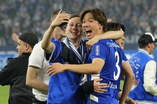 FILE - Schalke's Ko Itakura, right, celebrates with fans on the pitch the team's promotion to the Bundesliga after the 2nd Bundesliga soccer match against FC St. Pauli at the Arena in Gelsenkirchen, Germany, Saturday, May 7, 2022. Borussia Mönchengladbach signed Japan defensive midfielder Ko Itakura from Manchester City on Saturday, July 2, 2022 after seeing the role he played in helping Schalke return to the Bundesliga. (AP Photo/Martin Meissner, File)