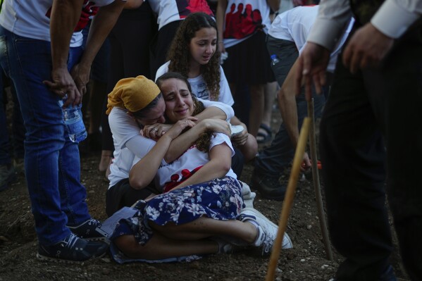 Mourners gather around the graves of British-Israelis Lianne Sharabi and her two daughters, Noiya,16, and Yahel,13, during their funeral in Kfar Harif, Israel, Wednesday, Oct. 25, 2023. Lianne Sharabi and her two daughters were killed by Hamas militants on Oct. 7 in kibbutz Be'eri near the border with the Gaza Strip. More than 1,400 people were killed and some 200 captured in an unprecedented, multi-front attack by the militant group that rules Gaza. (AP Photo/Ariel Schalit)