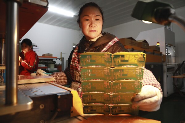A woman works at a factory of printed circuit board in Hangzhou in eastern China's Zhejiang province Sunday, Jan. 7, 2024. A survey of factory managers in China released Wednesday, Jan. 31, shows manufacturing contracted in January for a fourth straight month, reflecting weak demand and a faltering recovery in the world's second-largest economy. (Chinatopix Via AP)