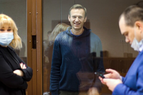 FILE - In this photo taken from a footage provided by the Babuskinsky District Court on Feb. 16, 2021, Russian opposition leader Alexei Navalny, center smiles as he talks with his lawyers Olga Mikhailova, left, and Vadim Kobzev during a hearing on his charges for defamation in the Babuskinsky District Court in Moscow, Russia. Mikhailova, a lawyer for imprisoned opposition leader Alexei Navalny said Tuesday that the authorities charged her with participating in an extremist group in absentia. (Babuskinsky District Court Press Service via AP, File)