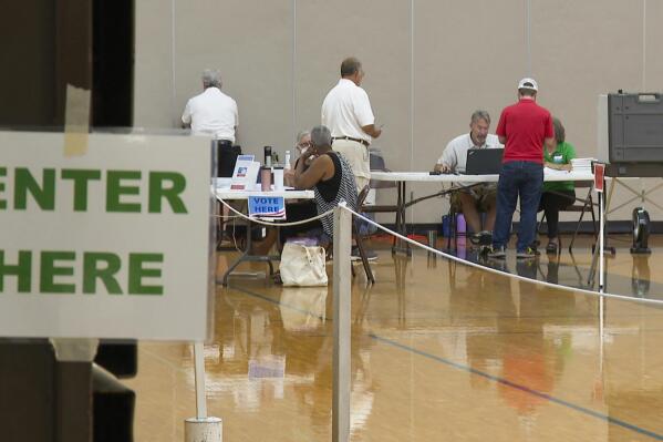 In this image from video, poll workers assist voters at a precinct in Delhi Township, Mich., near Lansing, on the day of the state’s primary election, Tuesday, Aug. 2, 2022. A shortage of poll workers has concerned local election officials across the country as the midterms approach. Not so in Michigan, where political operatives have recruited poll workers by the thousands. (AP Photo/Mike Householder)