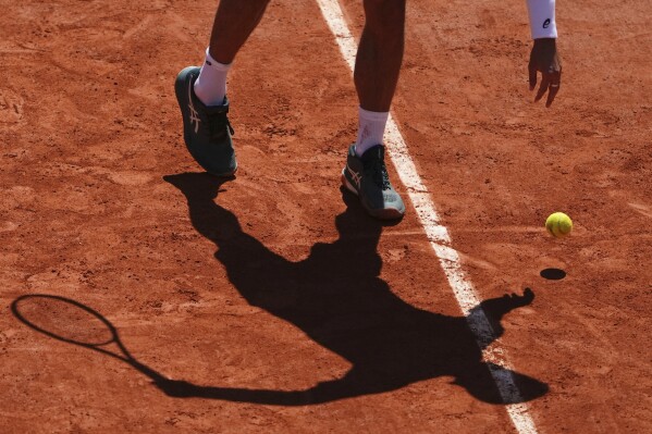Italy's Lorenzo Musetti casts his shadow on the court as he bounces the ball before serving to Argentina's Mariano Navone during their third round match of the French Tennis Open, at the Roland-Garros stadium, in Paris, Friday, May 30, 2025. (AP Photo/Lindsey Wasson)