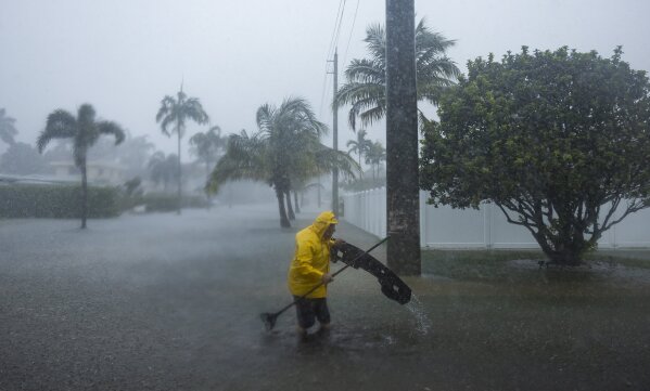 el miércoles 12 de junio de 2024 en Hollywood, Florida.  (Matthias J. Ochner/Miami Herald vía AP) Un hombre trabaja para retirar los escombros de una calle inundada después de que fuertes lluvias azotaran partes del sur de Florida.