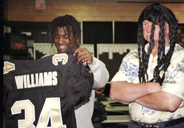 FILE - New Orleans Saints first-round draft pick Ricky Williams, left, checks out his New Orleans Saints jersey as coach Mike Ditka, wearing a dreadlock wig, looks on in Kenner, La., April 18, 1999. Ditka traded his entire 1999 draft class, plus first and third-rounders the following year to move up seven spots to draft Ricky Williams fifth overall. Williams lasted just three seasons with the Saints. (AP Photo/Judi Bottoni, File)