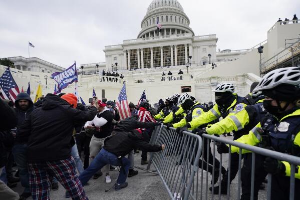 FILE - In this Jan. 6, 2021, file photo, Trump supporters try to break through a police barrier at the Capitol in Washington. A Chicago police officer has been charged with breaching the U.S. Capitol and entering a senator's office during the Jan. 6 insurrection. Karol Chwiesiuk, was arrested Friday, June 11 and faces five misdemeanor counts, including entering a restricted building, disrupting government business, and disorderly conduct on Capitol grounds with intent to impede congressional proceeding. (AP Photo/Julio Cortez, File)
