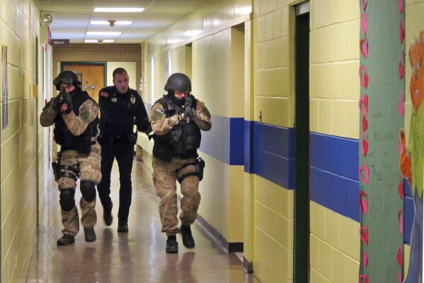 
              FILE - In this Jan. 28, 2013, file photo, members of the Washington County Sheriff's Office and the Hudson Falls Police Department use unloaded guns to take part in an emergency drill as they walk through a corridor inside the Hudson Falls Primary School in Hudson Falls, N.Y. With each subsequent shooting forcing schools to review their readiness, parents are increasingly questioning elements of the ever-evolving drills that are now part of most emergency plans, including the use of simulated gunfire and blood, when to reveal it’s just practice, and whether drills unduly traumatize kids. (Omar Ricardo Aquije/The Post-Star via AP, File)
            