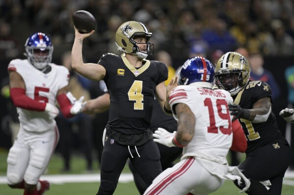 New Orleans Saints quarterback Derek Carr (4) throws under pressure from New York Giants safety Isaiah Simmons (19) during the first half of an NFL football game Sunday, Dec. 17, 2023, in New Orleans. (AP Photo/Matthew Hinton)