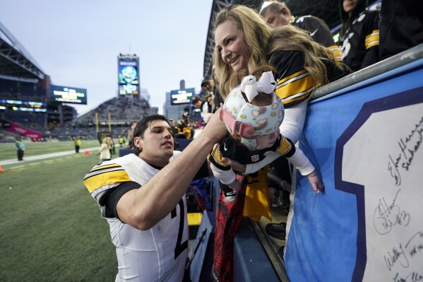 Pittsburgh Steelers quarterback Mason Rudolph autographs a baby's jersey after an NFL football game against the Seattle Seahawks Sunday, Dec. 31, 2023, in Seattle. The Steelers won 30-23. (AP Photo/Lindsey Wasson)