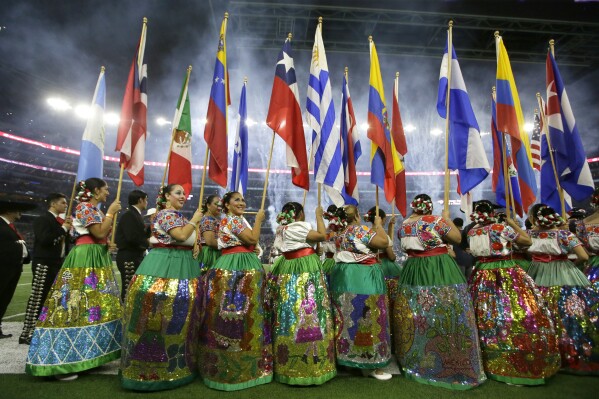 FILE - Dancers with the Ballet Folklorico De San Antonio carry flags from different Latin countries as they participate in a ceremony celebrating Hispanic Heritage Month before an NFL football game between the Chicago Bears and Dallas Cowboys, Sept. 25, 2016, in Arlington, Texas. Hispanic history and culture take center stage across the U.S. for National Hispanic Heritage Month. The celebration recognizes contributions made by Hispanic Americans, the fastest-growing racial or ethnic minority according to the Census, and with a U.S. population of over 63 million people, there will be a plethora of Hispanic Heritage Month celebrations all over the country starting Friday, Sept. 15, 2023. (AP Photo/LM Otero, File)