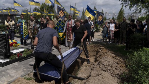 A coffin containing the remains of Roman Shadlovskyi is placed in a grave during his reburial in Bucha, Ukraine, Tuesday, July 18, 2023. The veteran of the Ukrainian armed forces, who was originally buried in a mass grave as a victim Unidentified after being killed last year by Russian troops, he was reburied on Tuesday after a DNA test confirmed his identity.  (AP Photo/Jae C. Hong)