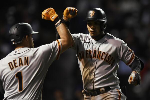 San Francisco Giants' Thairo Estrada, right, celebrates with teammate Austin Dean (1) after hitting a solo home run during the seventh inning of a baseball game against the Chicago Cubs Sunday, Sept. 11, 2022, in Chicago. (AP Photo/Paul Beaty)
